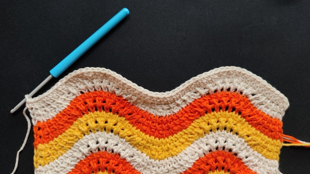 Feather and fan Tunisian crochet pattern for a washcloth 8 Top row of the wavy fabric, bound off with single crochet stitches in the same color as the last section, light beige.