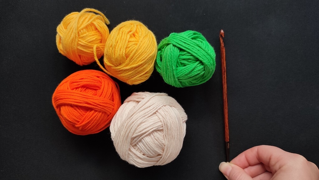 Feather and fan Tunisian crochet pattern for a washcloth 3 Balls of cotton yarn in orange, yellow, green and light beige, with a Tunisian crochet hook of 5 mm