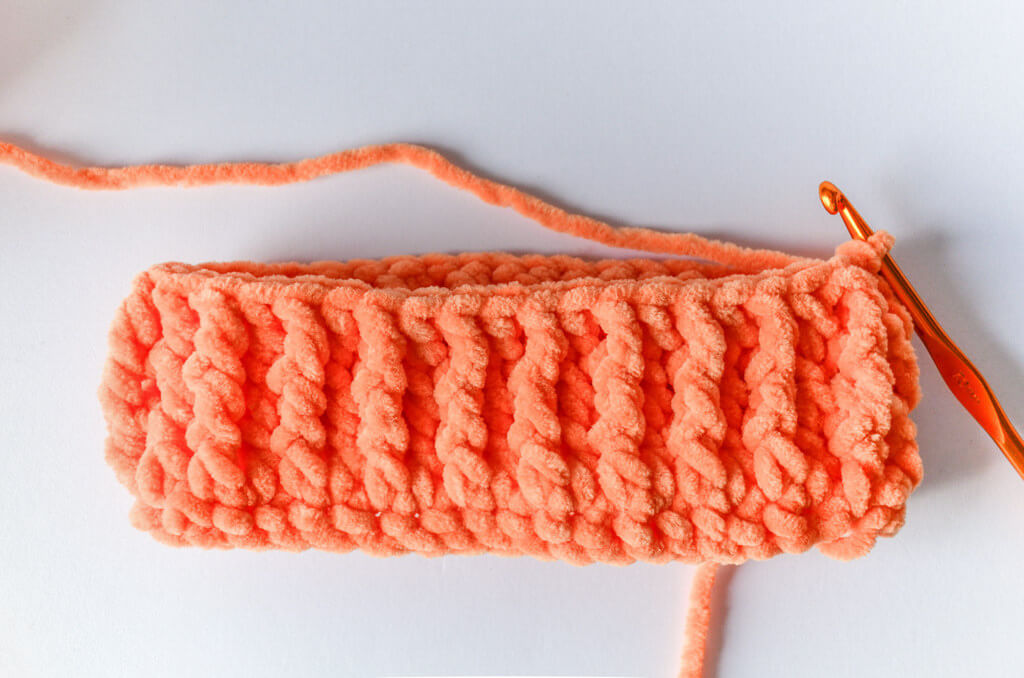 Free crochet pumpkin pattern 4 Partway through chenille crochet pumpkin body, with ridges created by front post stitches.