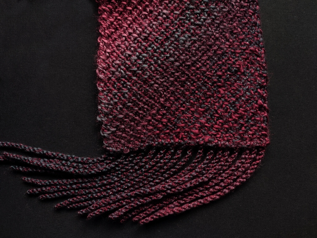 Corner to corner Tunisian crochet scarf pattern 4 Close-up of fringe on the end of the Tunisian crochet scarf, showing as well the marled nature of the fabric made on the bias in a yarn where one strand changes color independently of the second strand in the ply.