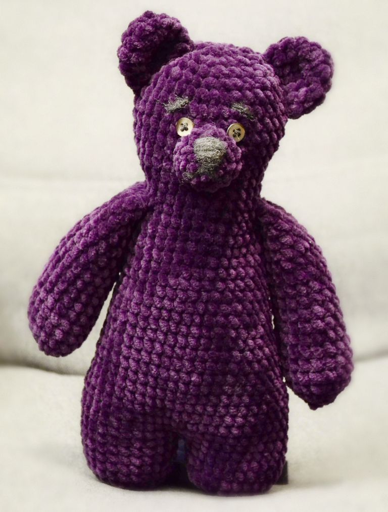 Full view of the amigurumi teddy bear with long arms and very short legs.