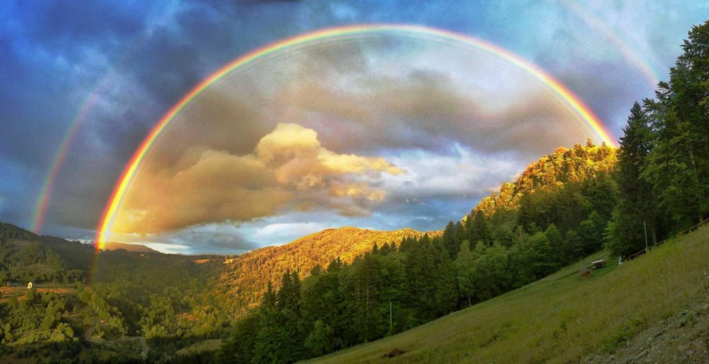 Full double rainbow over mountains in Romania