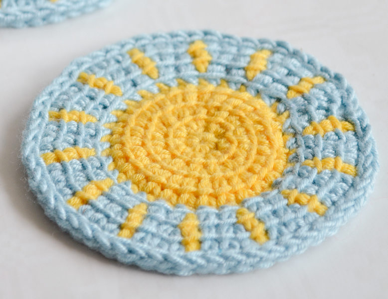 Little sun Tunisian crochet coaster pattern on a table