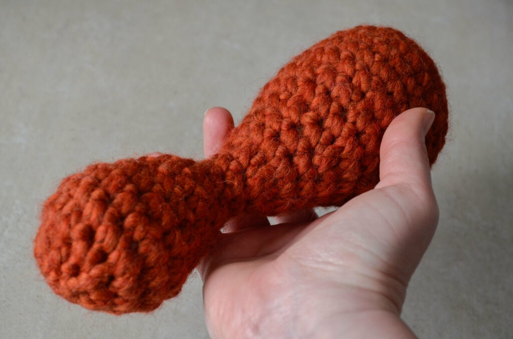 Large orange wool crochet fidget toy held in a hand