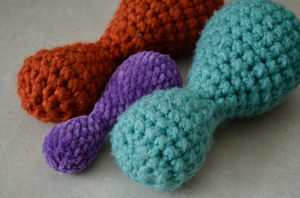 Three different crochet fidget toys in one image, from left to right: super bulky wool, baby chenille yarn, super bulky acrylic
