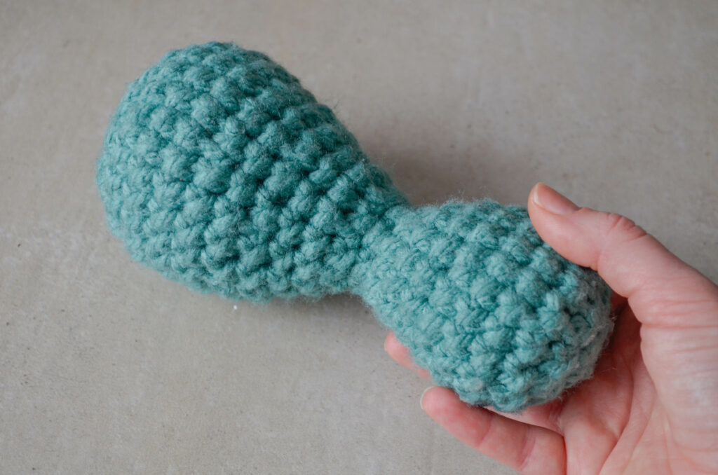 Light blue skittle crochet fidget toy held with one hand