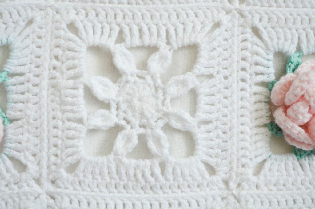 Simple flower granny square in baby blanket next to flower square